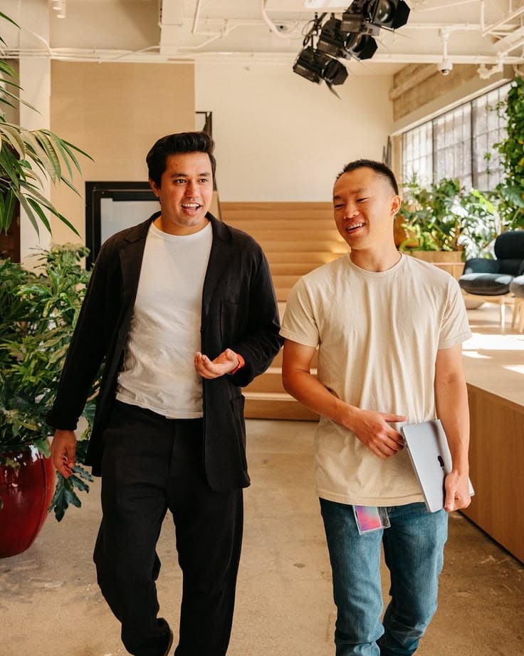Two colleagues walking and talking through a sunlit office